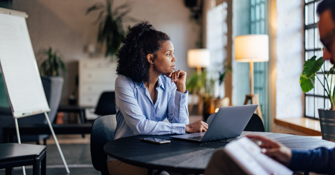 Ein offener Coworkingspace in dem Menschen an Schreibtischen sitzen und an Laptops arbeiten